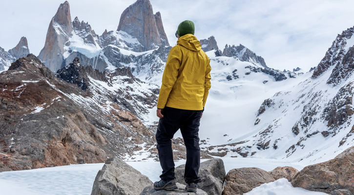 hiker wearing yellow jacket hiking on snowy mountains