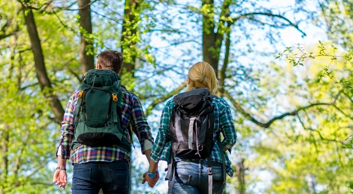 couple with backpacks hiking in the forest