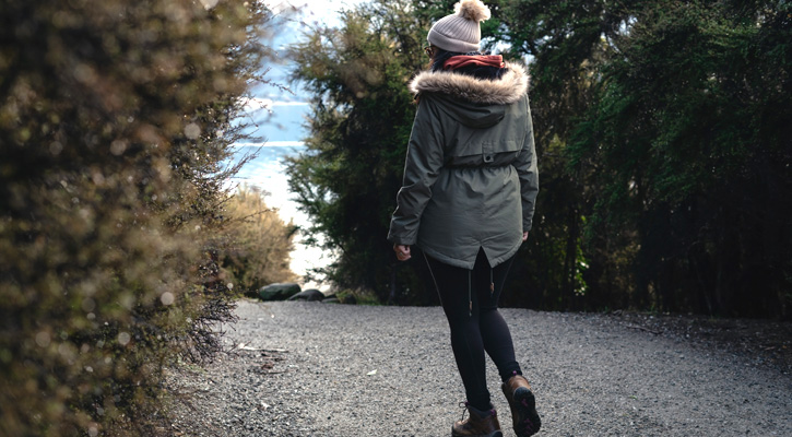 woman wearing winter jacket walking in a forest street