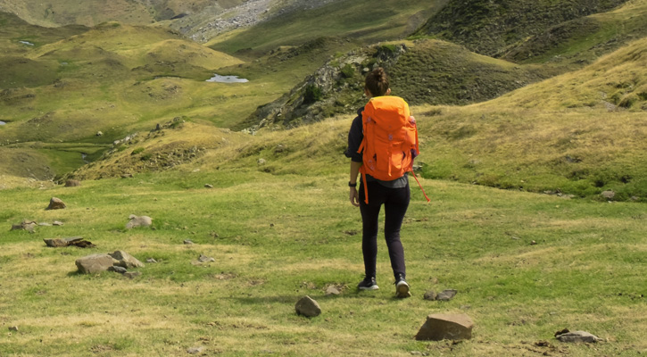 woman with a backpack hiking on a mountain trail