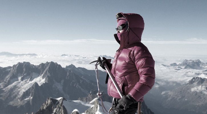 climber wearing down jacket on top of a mountain