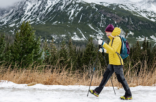 woman wearing down jacket hiking on snowy trail